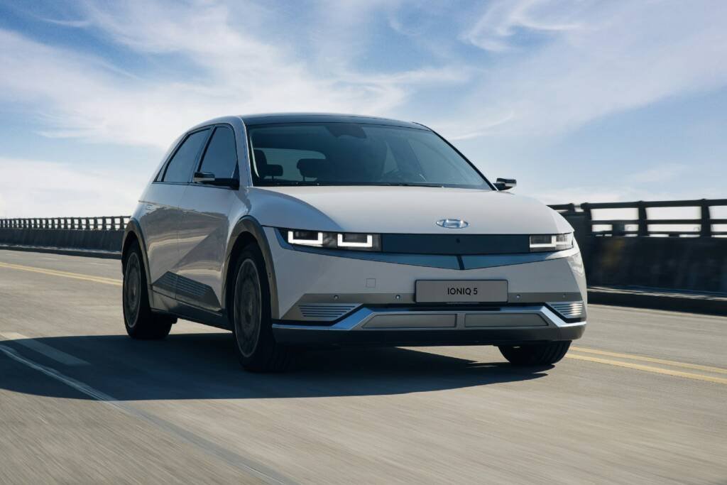White Hyundai Ioniq 5 electric SUV driving across a bridge on a clear day