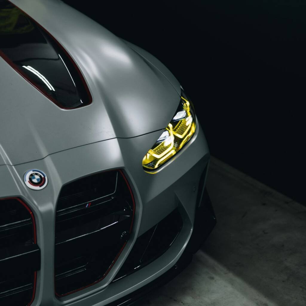 Matte grey BMW M4 front end with bright yellow headlights