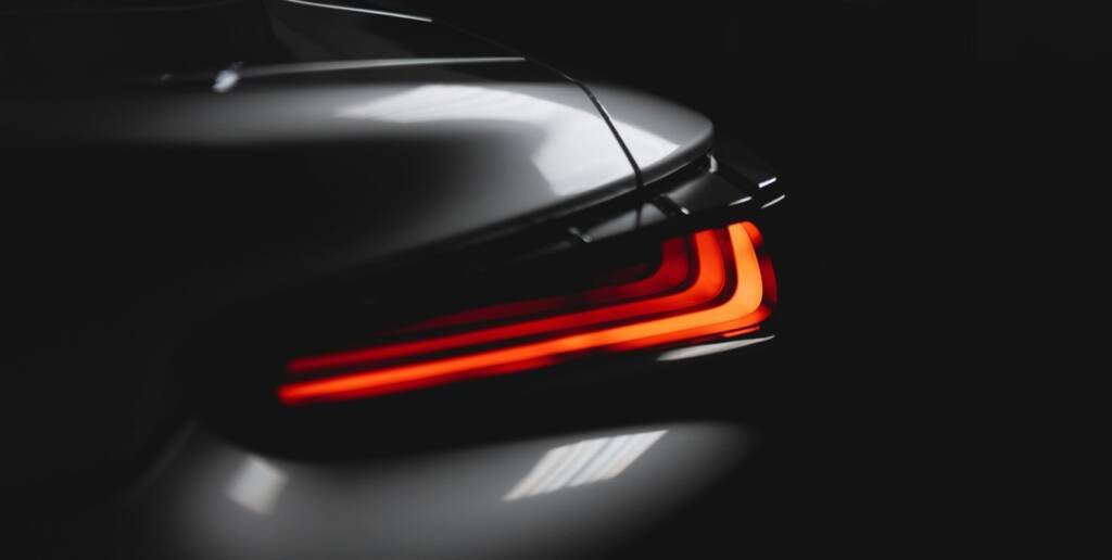 Sculpted LED tail light of a dark coupe in a studio